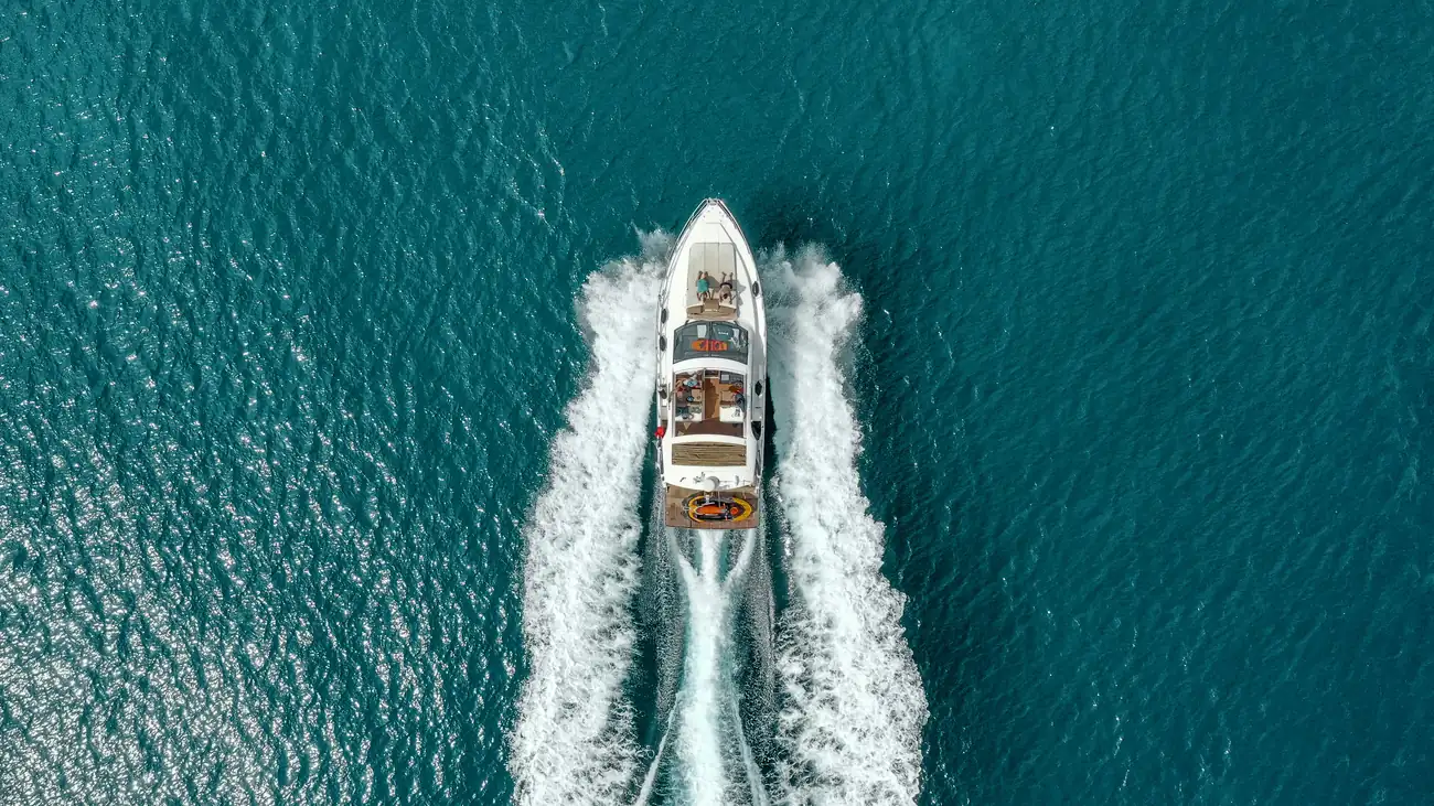 A boat cutting a wake through deep teal water