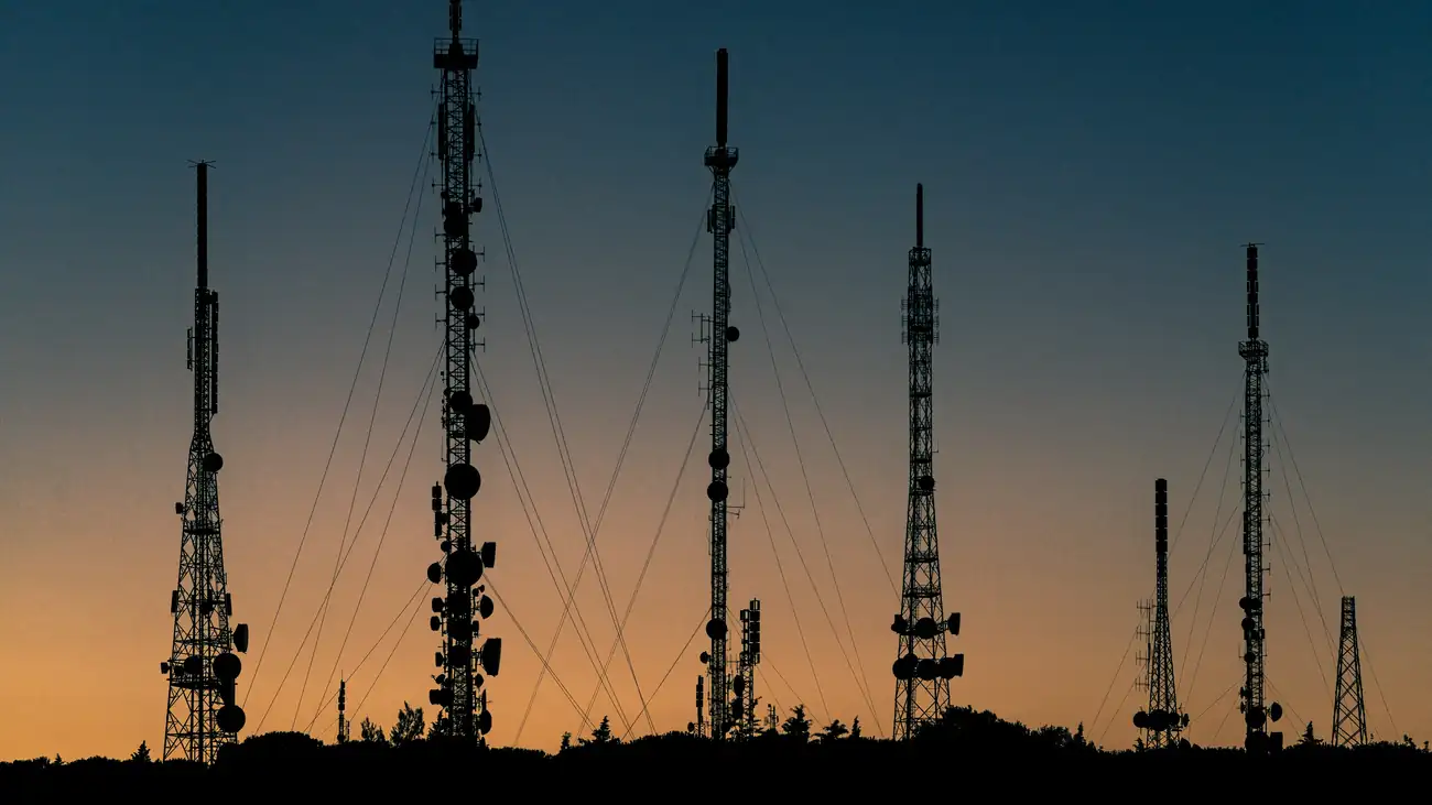 Communication towers silhouetted against an evening sky