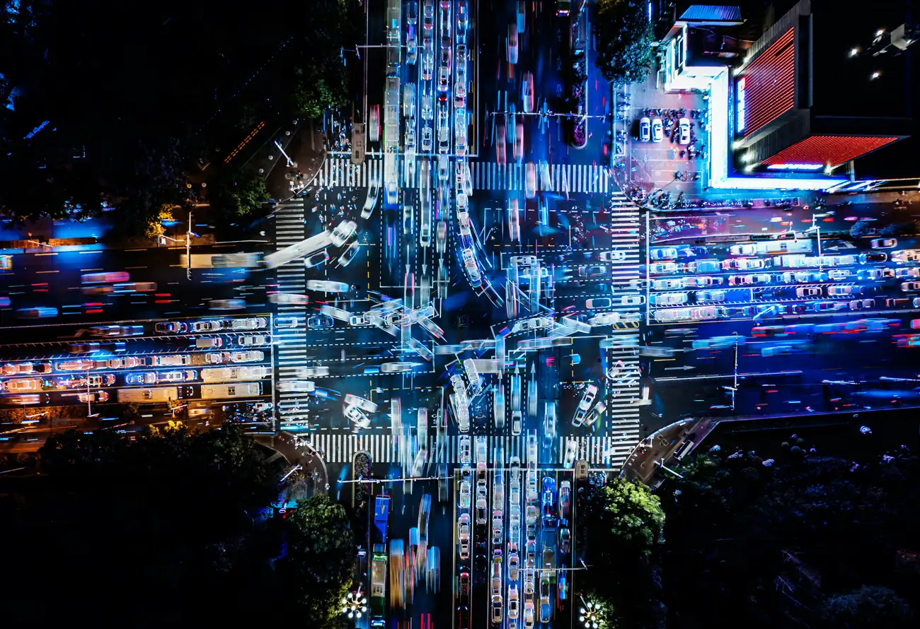 An aerial night view of traffic moving through a city intersection